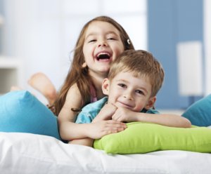 Portrait of two smiling siblings lying on cushions